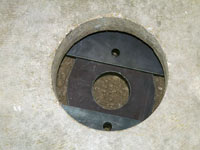 A three piece foundation slab bracket assembled underneath a concrete slab floor.