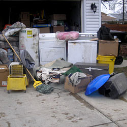 Soaked, wet personal items sitting in a driveway, including a washer and dryer in Maple Grove.