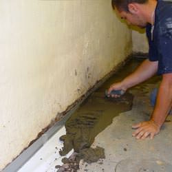 A basement waterproofer installing a perimeter drain system in Newport